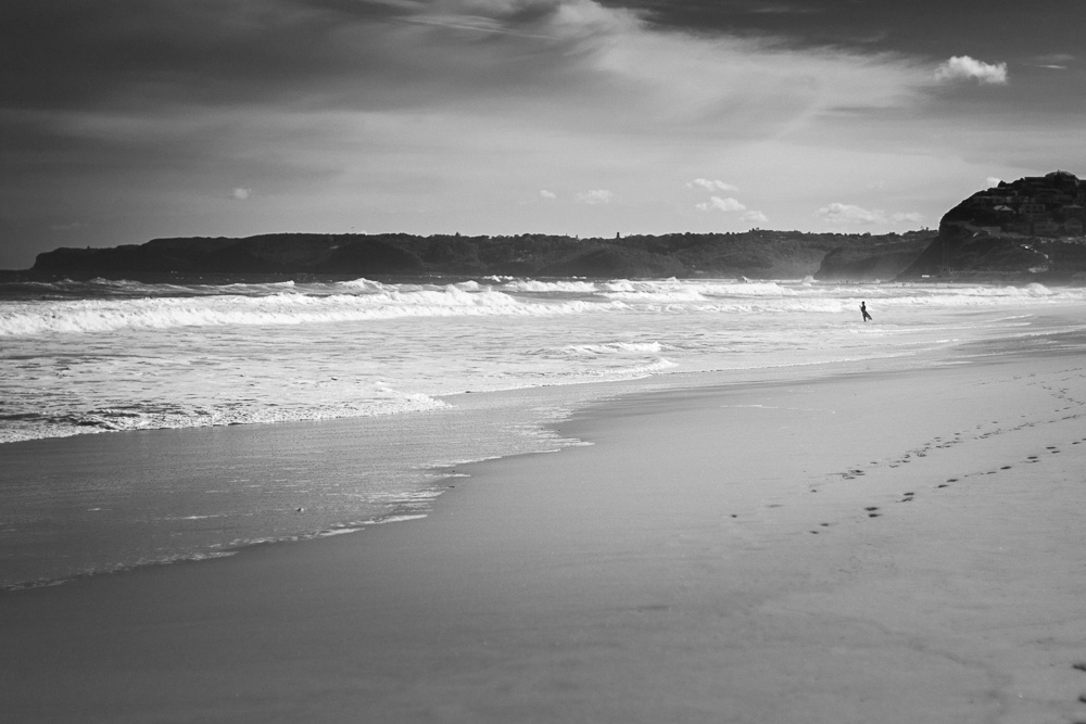 black and white beach and surfer photograph
